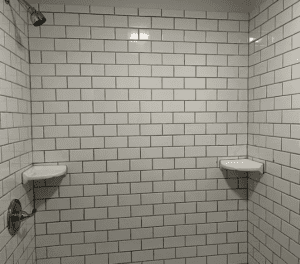 A white tiled bathroom with two sinks and a shower.