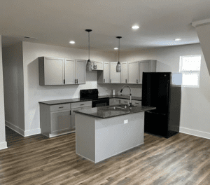 A kitchen with an island and black refrigerator.
