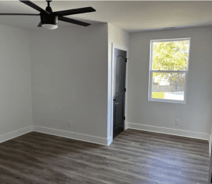 A room with a black door and a ceiling fan.