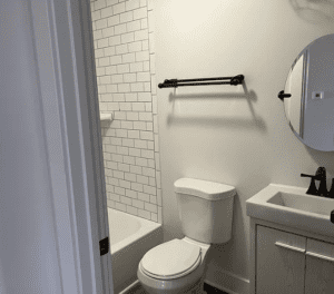 A bathroom with white tile and black accents.