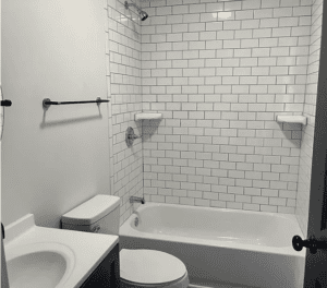 A bathroom with white tile and black accents.